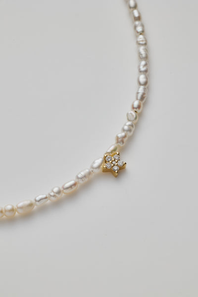 Delicate bracelet with lustrous pearls and a diamond star charm, elegantly crafted.