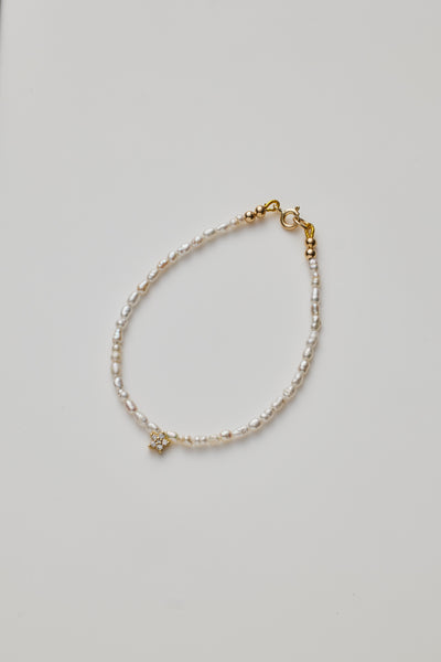 Delicate bracelet with lustrous pearls and a diamond star charm, elegantly crafted.