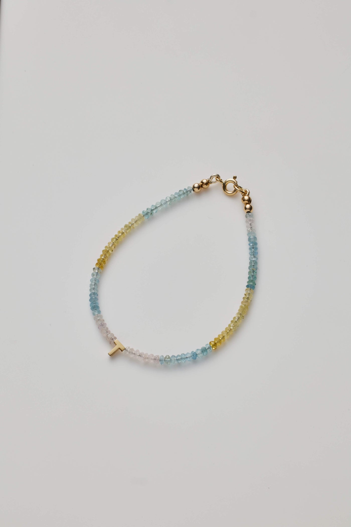 14K gold letter P necklace strung with naturally shaded aquamarine gemstones, showcasing ocean-inspired hues.