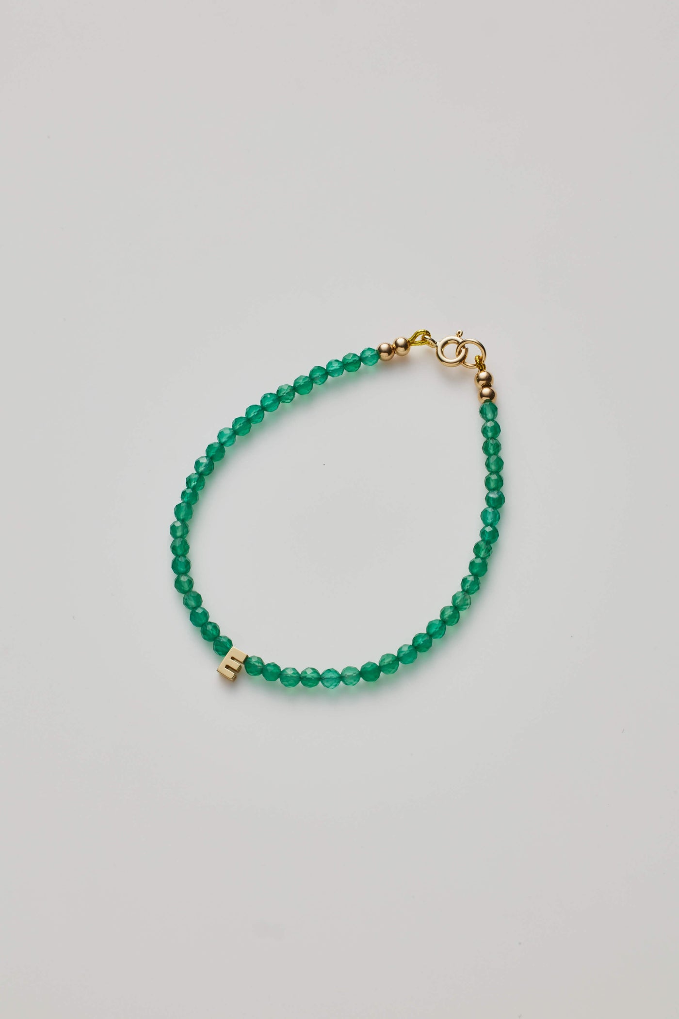 Green onyx gemstone bracelet with a gold letter charm.