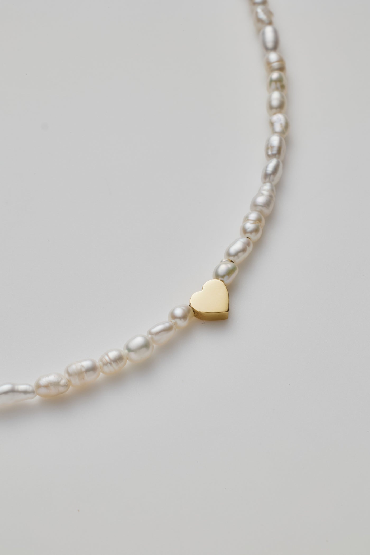 Delicate bracelet with lustrous pearls and a gold heart charm, elegantly crafted.