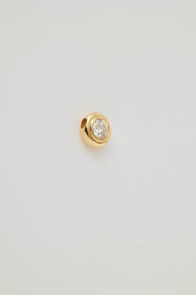 Side view photograph of an April Birthstone Charm set featuring a genuine diamond in a gold bubble setting. The charm sparkles with elegance, showcasing its intricate craftsmanship against a soft, neutral background.