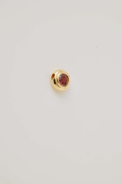 Side view image of the January Birthstone Charm featuring a rich red garnet gemstone in a polished gold setting. 