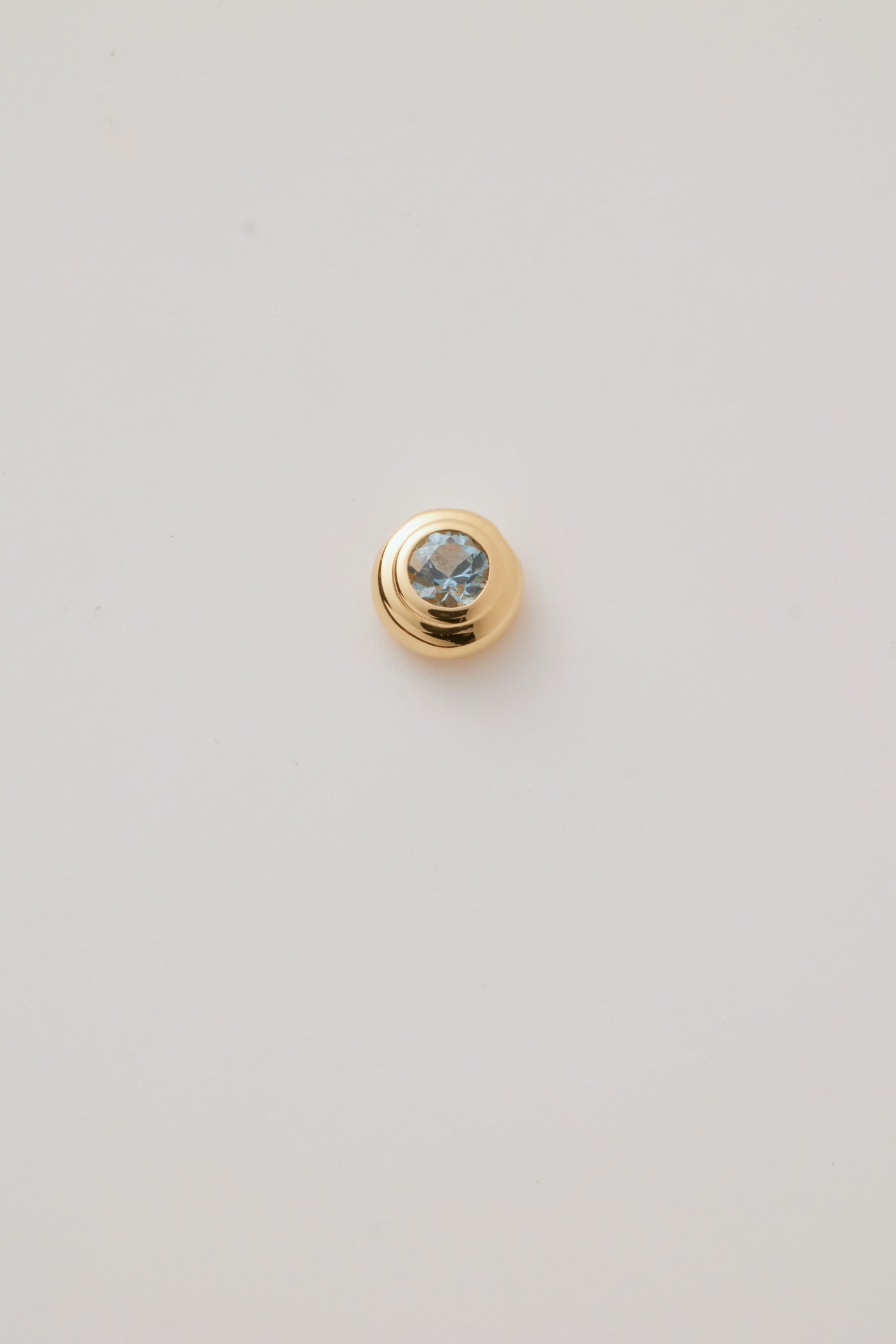 Close-up image of a March Birthstone Charm featuring a serene aquamarine gemstone in a sleek gold setting, showcasing soft blue tones. 