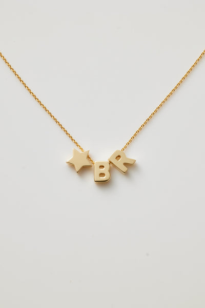 The Two Letters and Star Necklace in 18k Gold is a delicate piece featuring three charms: the letters "B" "R" separated by a small star, all suspended from a fine chain with an openable connector clasp. The plain white background highlights the simplicity and elegance of this exquisite necklace.