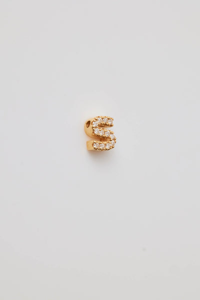 A diamond letter charm is photographed side-on to show the depth of the charm. The letter is pavé-set with sparkling diamonds, crafted to shimmer brilliantly under the light. Each diamond is precisely set to create a seamless, radiant surface that enhances the charm's elegance. The letter's shape is bold yet refined, with smooth, polished edges that provide a striking contrast to the intricate diamond detailing.