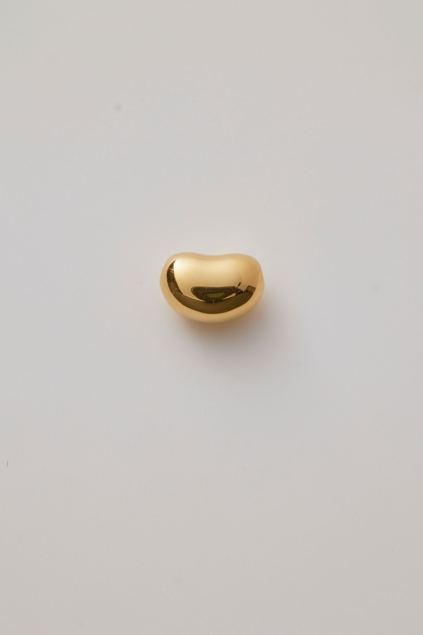 Small gold bean-shaped charm with a smooth, polished finish and hole through the centre for threading a necklace chain. 