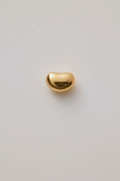 Small gold bean-shaped charm with a smooth, polished finish and hole through the centre for threading a necklace chain. 