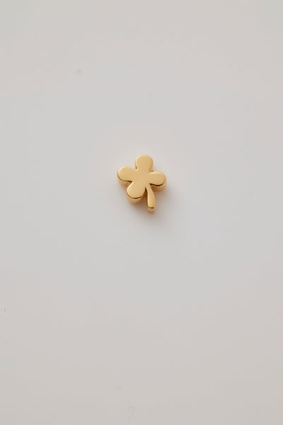 The reverse side of a gold four-leaf clover charm with smooth, rounded leaves.  