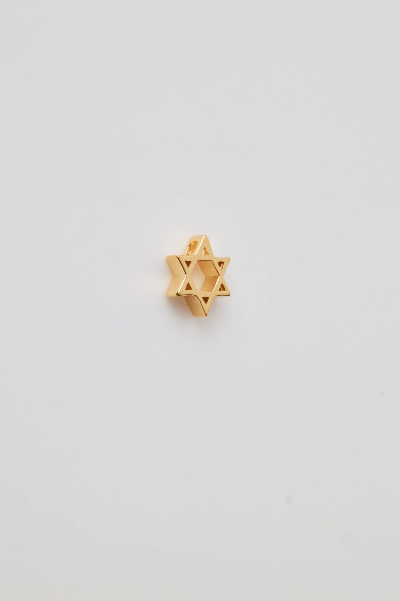 The side view of a Star of David charm made from polished 18-karat gold with a sleek finish. The charm features two interlocking triangles that create the iconic six-pointed star, symbolizing unity and heritage.