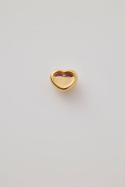 The back view of a pink cabochon stone set in a polished gold heart frame, dis isplayed on a light grey background. Elegant and timeless.