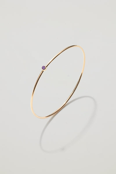 Solid gold bangle with a February amethyst birthstone, symbolising calm and clarity.