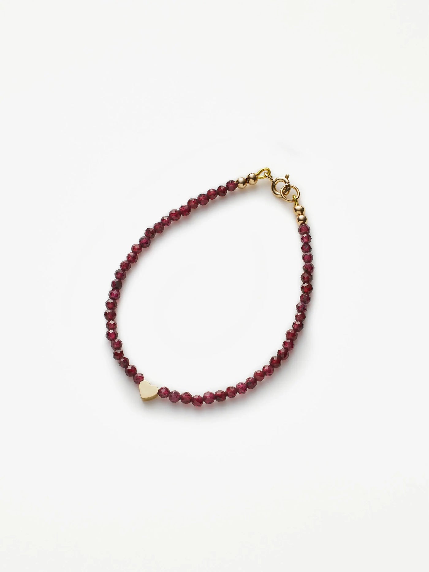 Introducing the Heart Bracelet in Garnet and 18k Gold: a delicate piece crafted with red garnet beads and accented by a small heart-shaped charm made from solid 18k gold. This simple and elegant bracelet features a gold clasp for secure fastening, making it an ideal accessory for any occasion. Custom sizes are offered to ensure the perfect fit. Photographed on a plain white background, this timeless design is sure to impress.