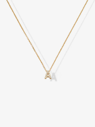 The Letter A Necklace in Diamonds and 18k Gold showcases a delicate pendant shaped like the letter "A," adorned with small, sparkling diamonds. Displayed against a plain, light background, the exquisite pendant hangs gracefully at the center of the image.

