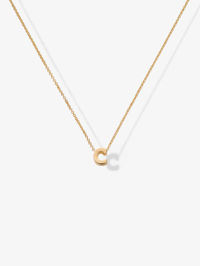 The Letter C Necklace in 18k Gold showcases a delicate, small charm in the shape of the letter "C." Laid out against a white background, the necklace's charm is centered with the chain symmetrically extending to either side and secured by openable connectors.