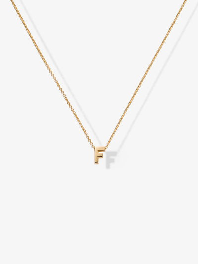 The Letter F Necklace in 18k Gold showcases a small, capital letter "F" pendant at the center of a delicate gold chain. The necklace's minimalistic design is enhanced by its thin chain and displayed elegantly against a plain white background.