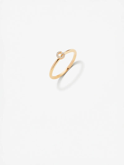 The Letter G Ring in Diamonds and 18k Gold, featuring a delicate design with a small circular setting adorned with brilliant diamonds, is displayed against a white background. The ring casts a slight shadow below, adding depth to the simple and elegant presentation.