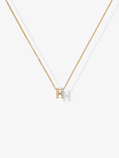 The Letter H Necklace in Diamonds and 18k Gold features a delicate 18k gold chain with a customizable "H" charm adorned with tiny, clear gemstones. The sparkling pendant adds an elegant touch to its simple yet stylish design, all beautifully showcased against a white background.