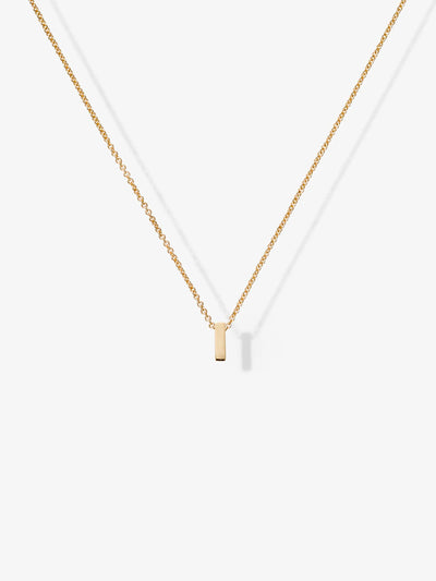 The Letter I Necklace in 18k solid gold features a small, rectangular gold pendant symmetrically centered on a delicate chain, casting a soft shadow on a white background.