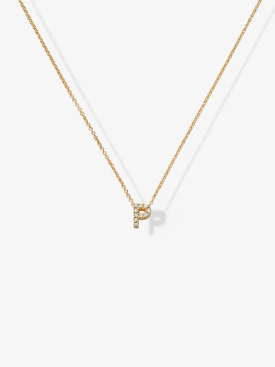 The Letter P Necklace in Diamonds and 18k Gold features a delicate 18k solid gold chain with a small, sparkling pendant shaped like the letter 'P,' adorned with tiny white crystals. The necklace hangs prominently in the center of the image against a plain white background.