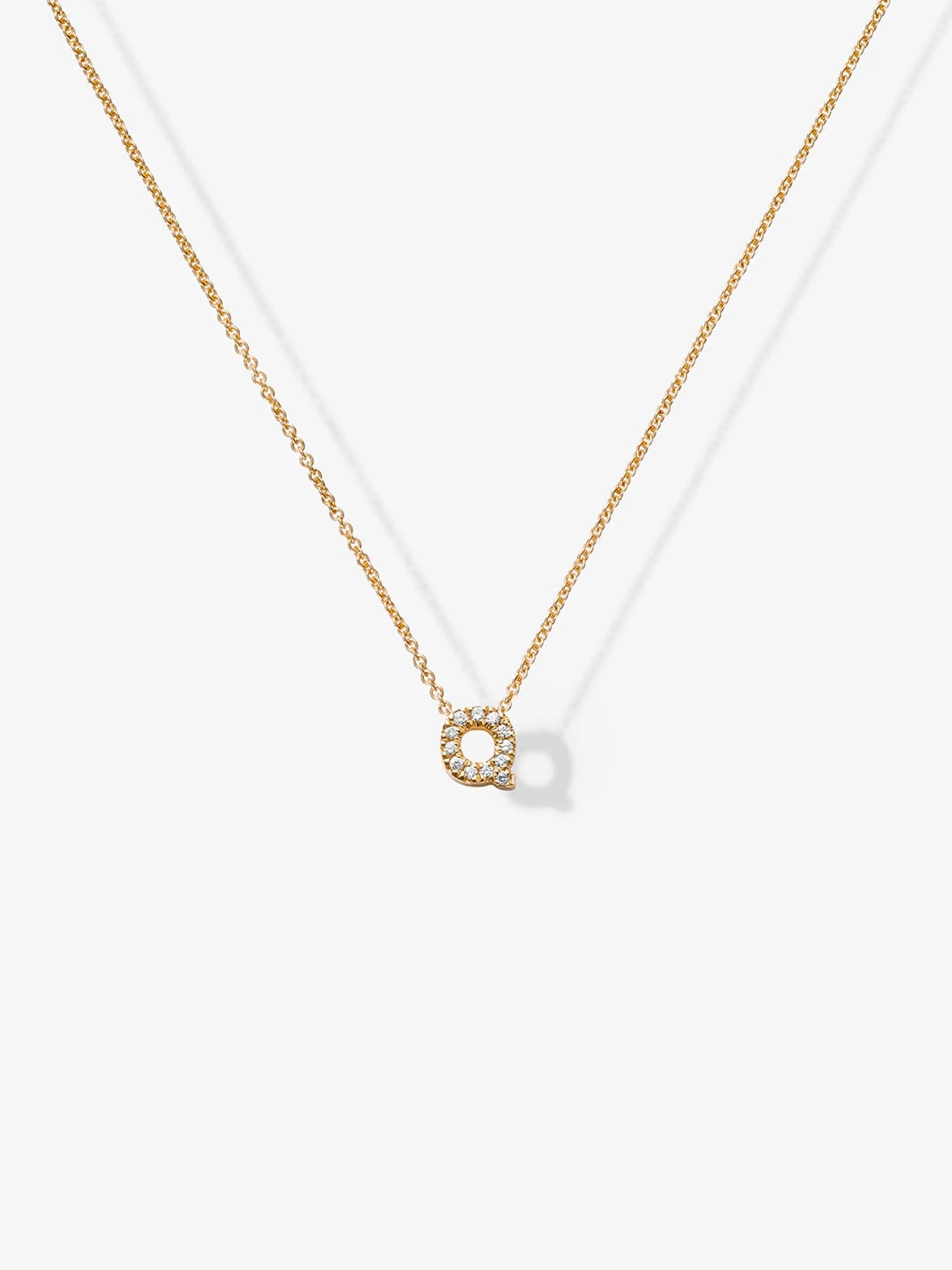 The Letter Q Necklace in Diamonds and 18k Gold features a sophisticated 18k gold necklace with a small, square-shaped pendant adorned with tiny diamonds. The customizable charm necklace is displayed against a plain white background.