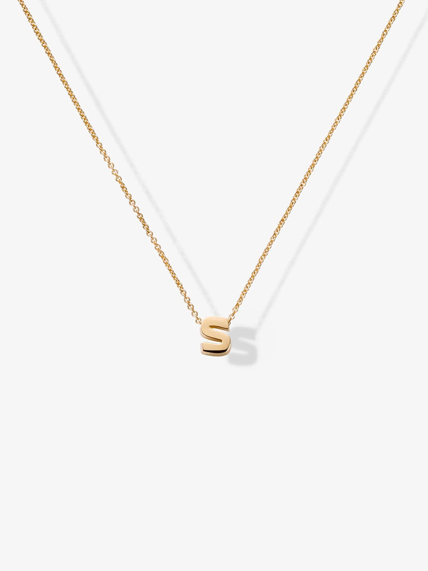 Product Description: The Letter S Necklace in 18k Gold features a delicate solid gold chain adorned with a small gold letter "S" pendant. Set against a plain white background, this exquisite piece highlights the simplicity and elegance of this refined necklace.