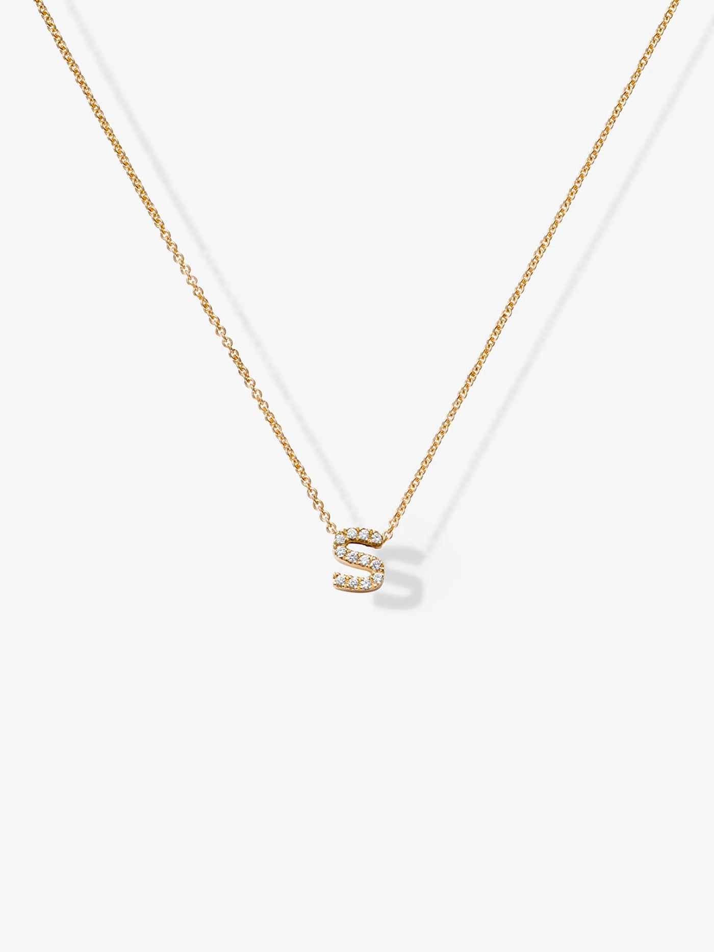 The Letter S Necklace in Diamonds and 18k Gold showcases a small, diamond-encrusted "S" pendant on a fine, 18k gold chain. Set against a plain, white background, the necklace's elegant simplicity is perfectly highlighted.