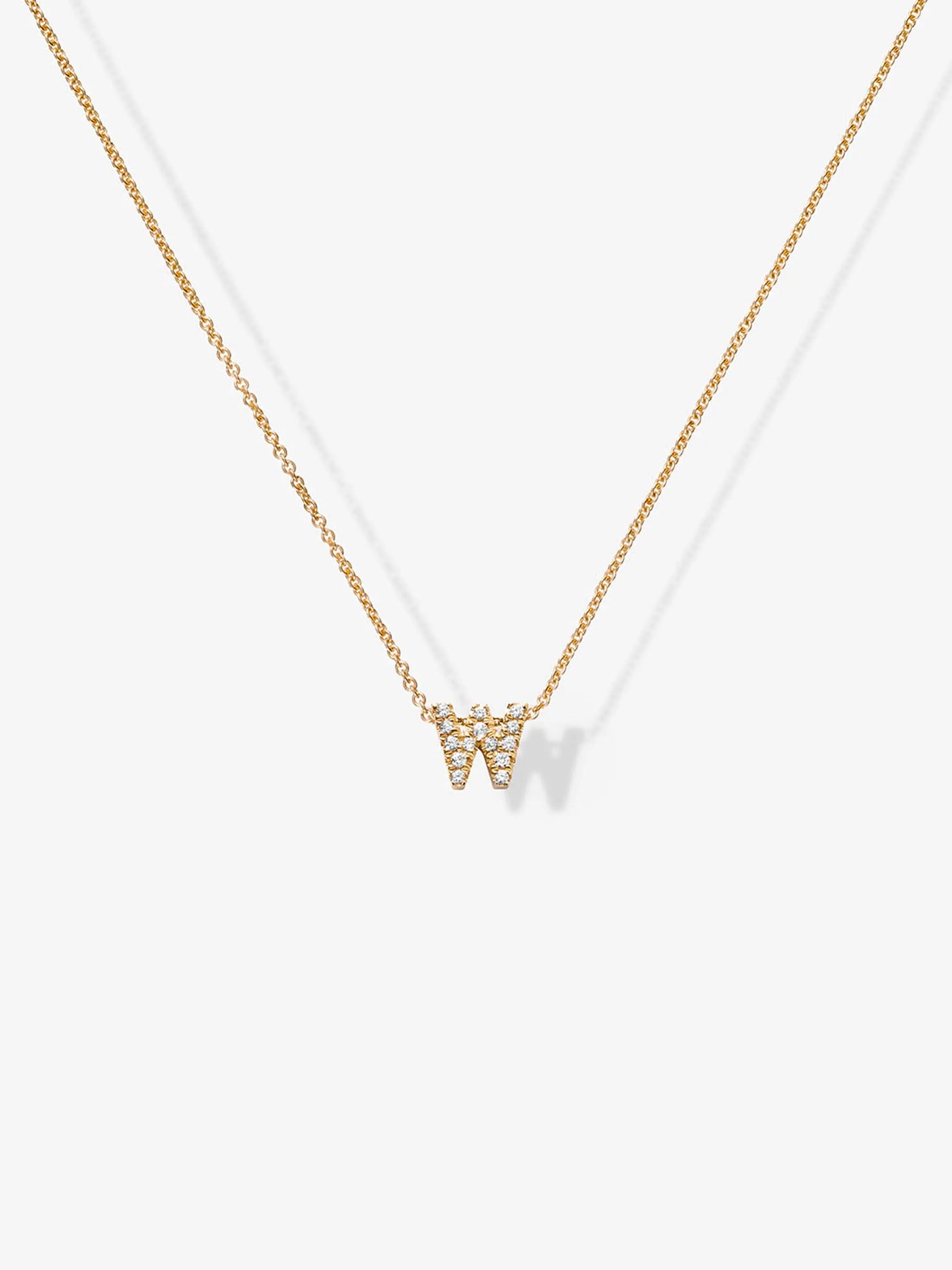 The "Letter W Necklace in Diamonds and 18k Gold" features a delicate 18k gold pendant shaped like the letter "W," adorned with small diamonds. The white background highlights the simplicity and elegance of this stunning diamond letter necklace.