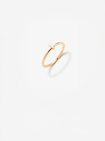 Close-up image of a personalised I gold ring adorned with intricate, miniature dimensional letters from the alphabet on a light grey background 