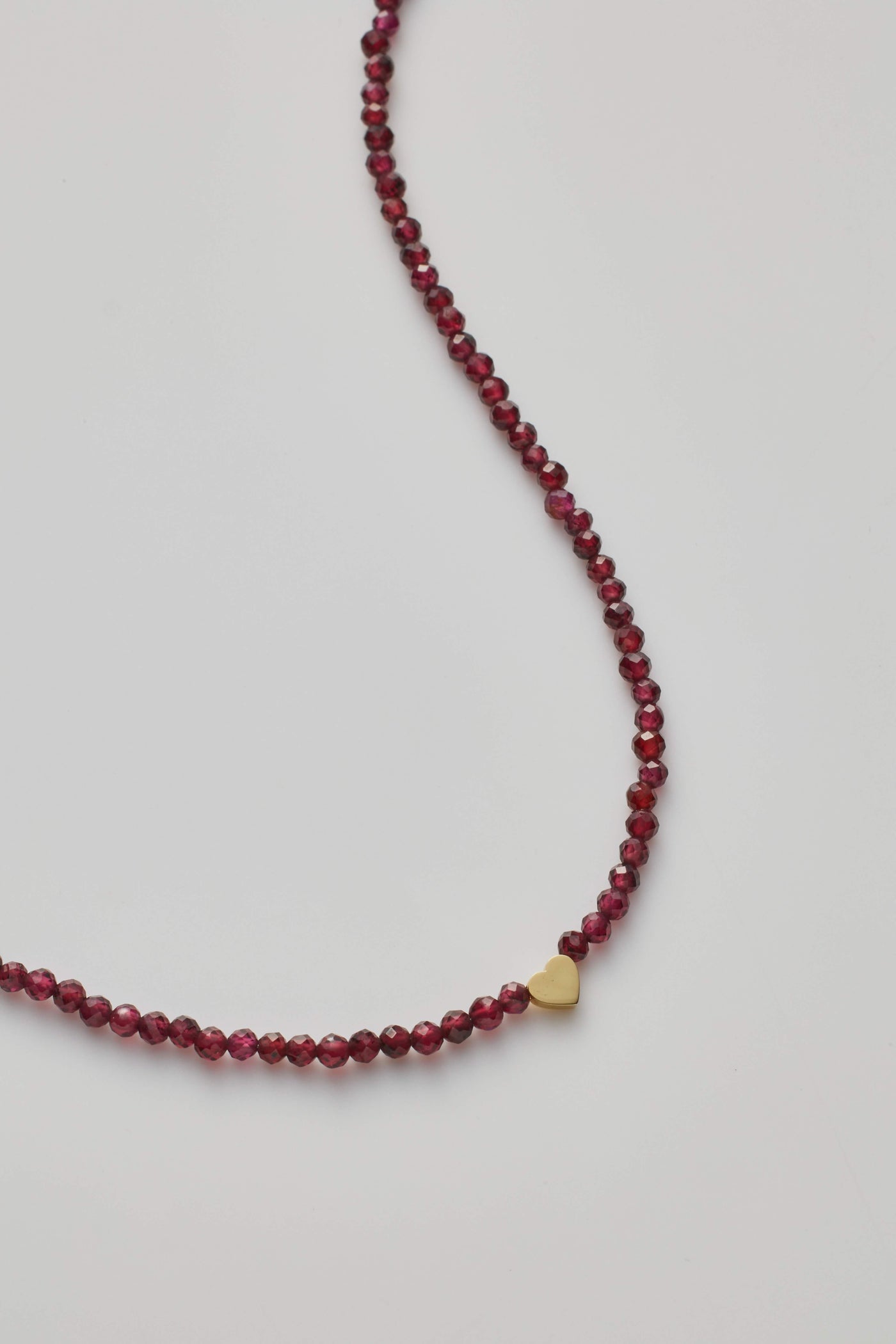 14K gold necklace with red garnet faceted crystals and a gold letter charm.